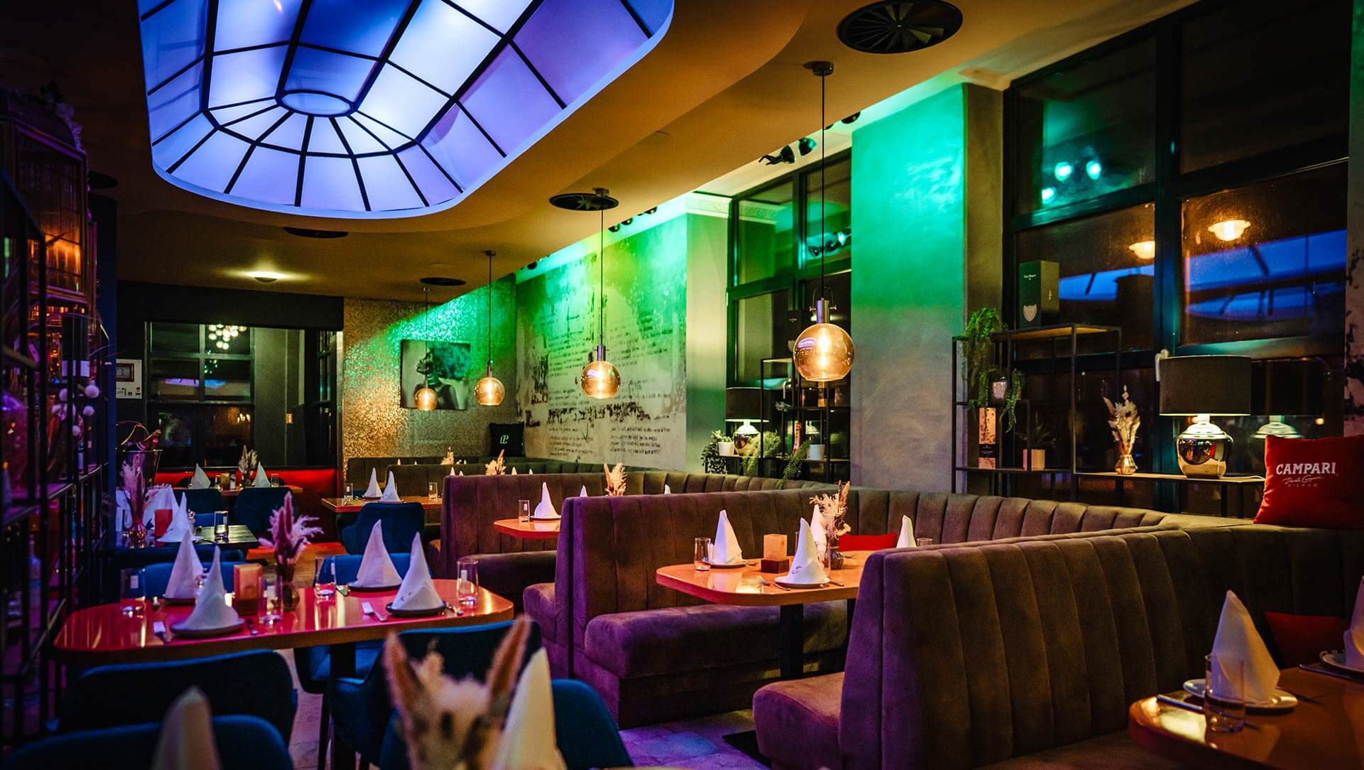 Cozy dining area at Al Porto with warmly lit benches and blue velvet chairs.