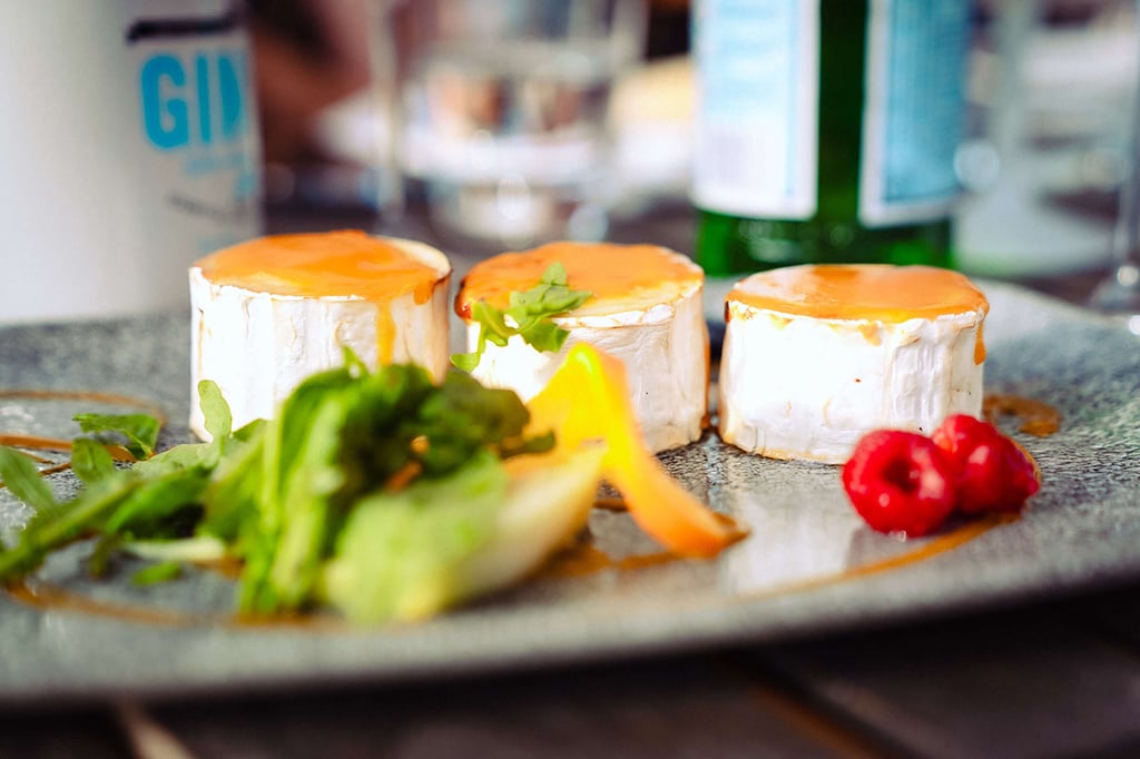 Antipasto con formaggio di capra gratinato, servito con rucola, arancia e lamponi dal ristorante italiano Al Porto.