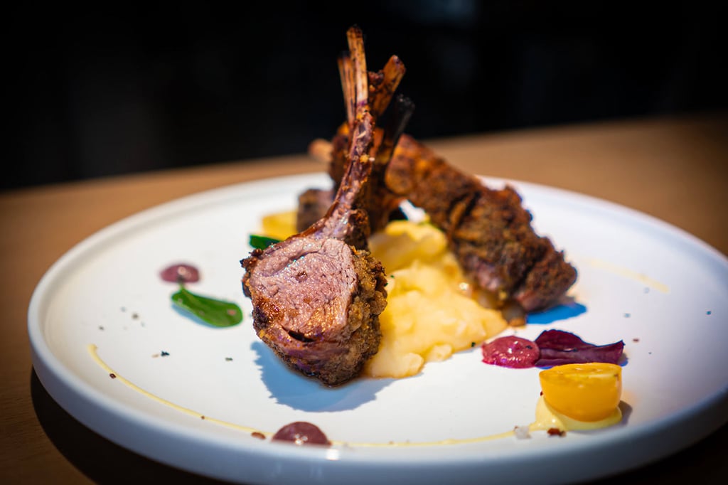 Elegantly presented rack of lamb from Italian restaurant Al Porto on creamy mashed potatoes with side dishes and sauce.
