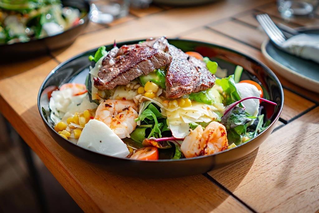 Insalata italiana con bistecca di manzo alla griglia, gamberetti e parmigiano.