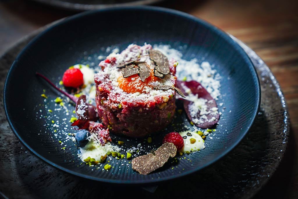 Exquisite beef tartare topped with fresh egg yolk and shaved black truffle.