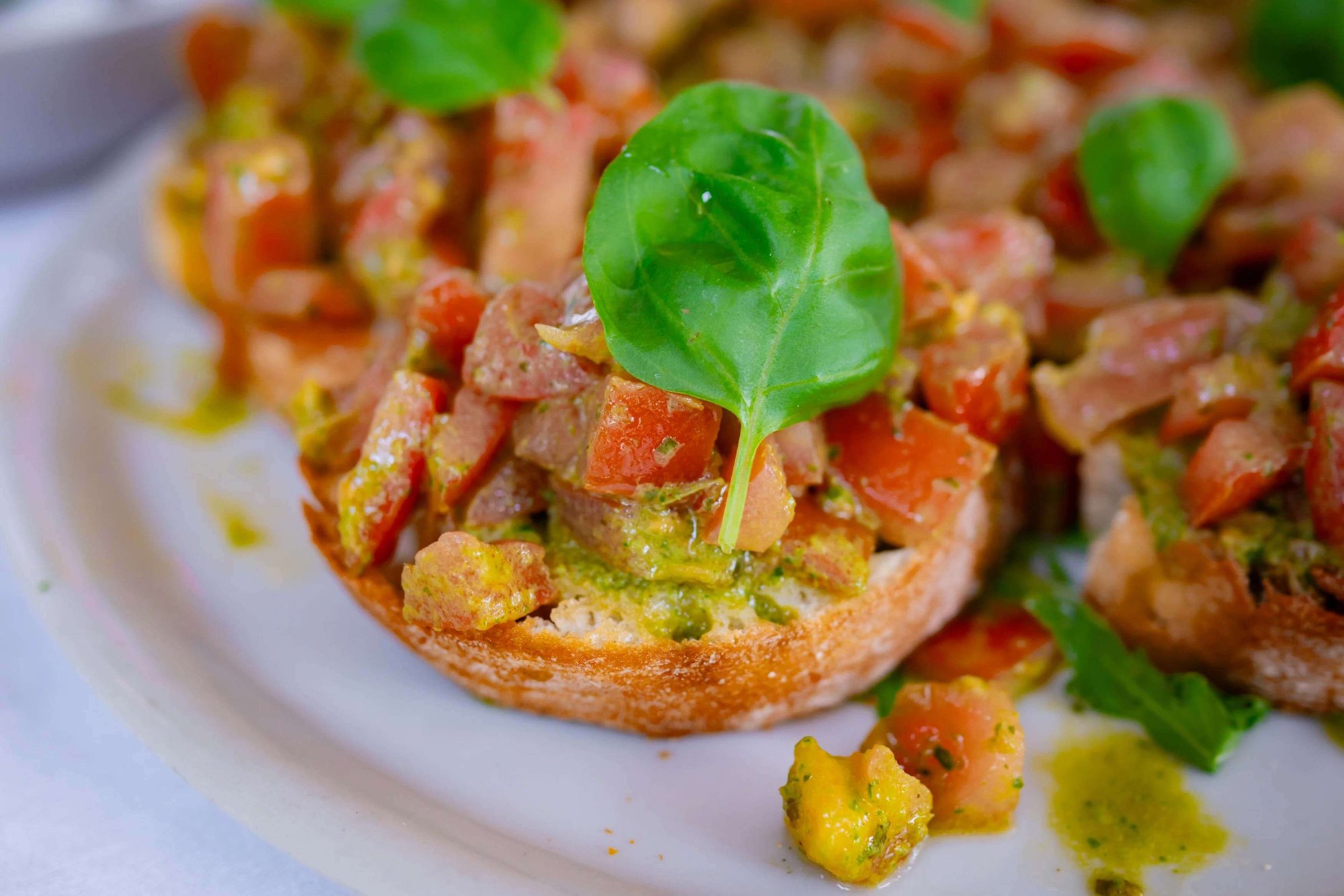 Klassische italienische Bruschetta vom Italiener in Rostock mit marinierten Tomaten und frischem Basilikumblatt.