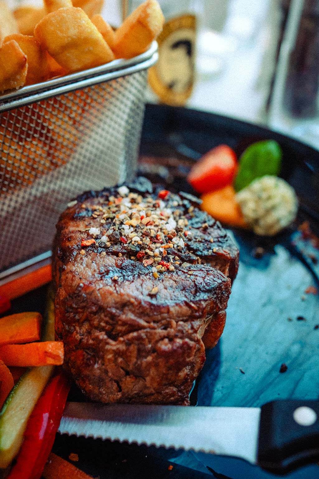 Vom Rostocker Italiener perfekt gebratenes Rinderfilet mit Pfefferkruste, Pommes Frites im Korb und Kräuterbutter.