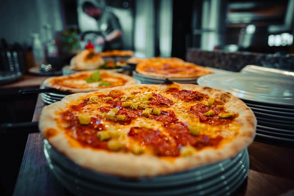 Nahaufnahme einer ofenfrischen, knusprigen Pizza mit Salami und Pilzen vom Italiener Al Porto in Rostock.