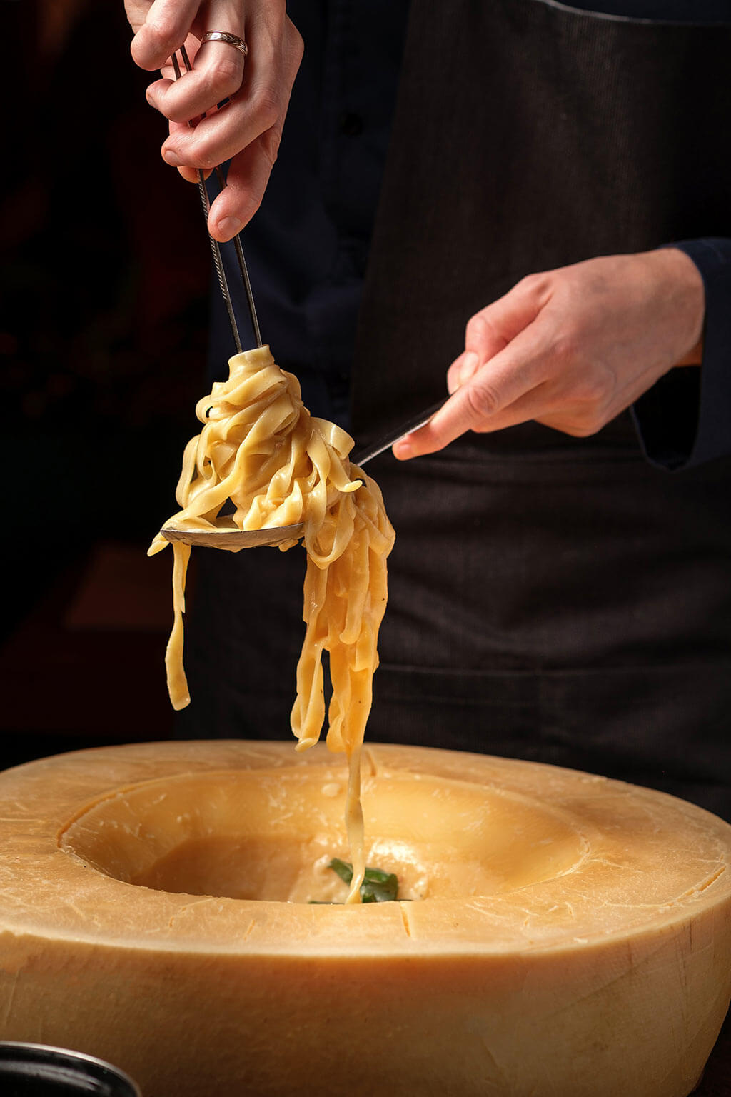 Authentic Italian pasta is freshly tossed by hand directly in a large wheel of Parmesan cheese.
